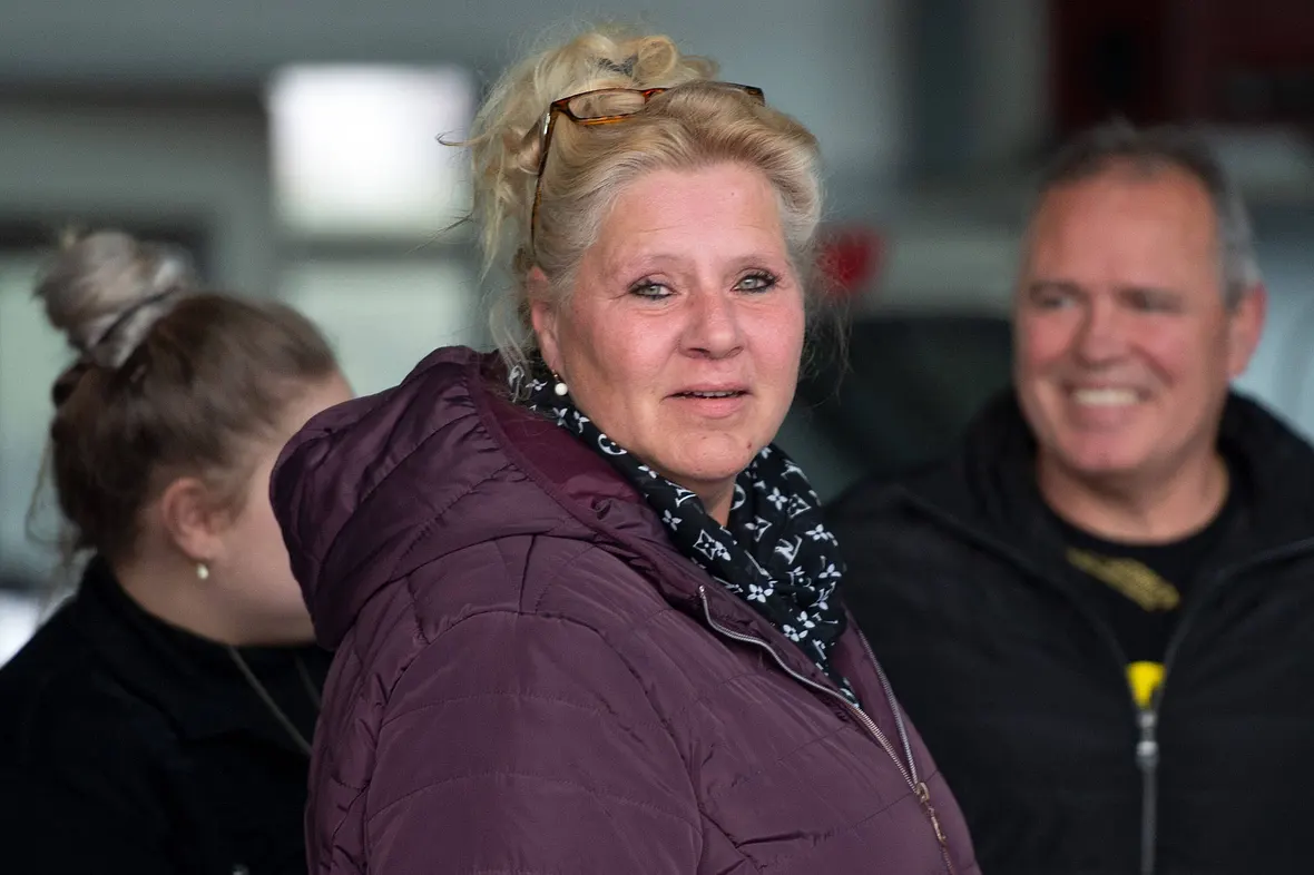 Silvia Wollny steht im Vordergrund und schaut in die Kamera. Sie trägt eine Lila-farbene Winterjacke. Im Hintergrund erkennt man unscharf ihren Lebensgefährten Harald Elsenbast. 