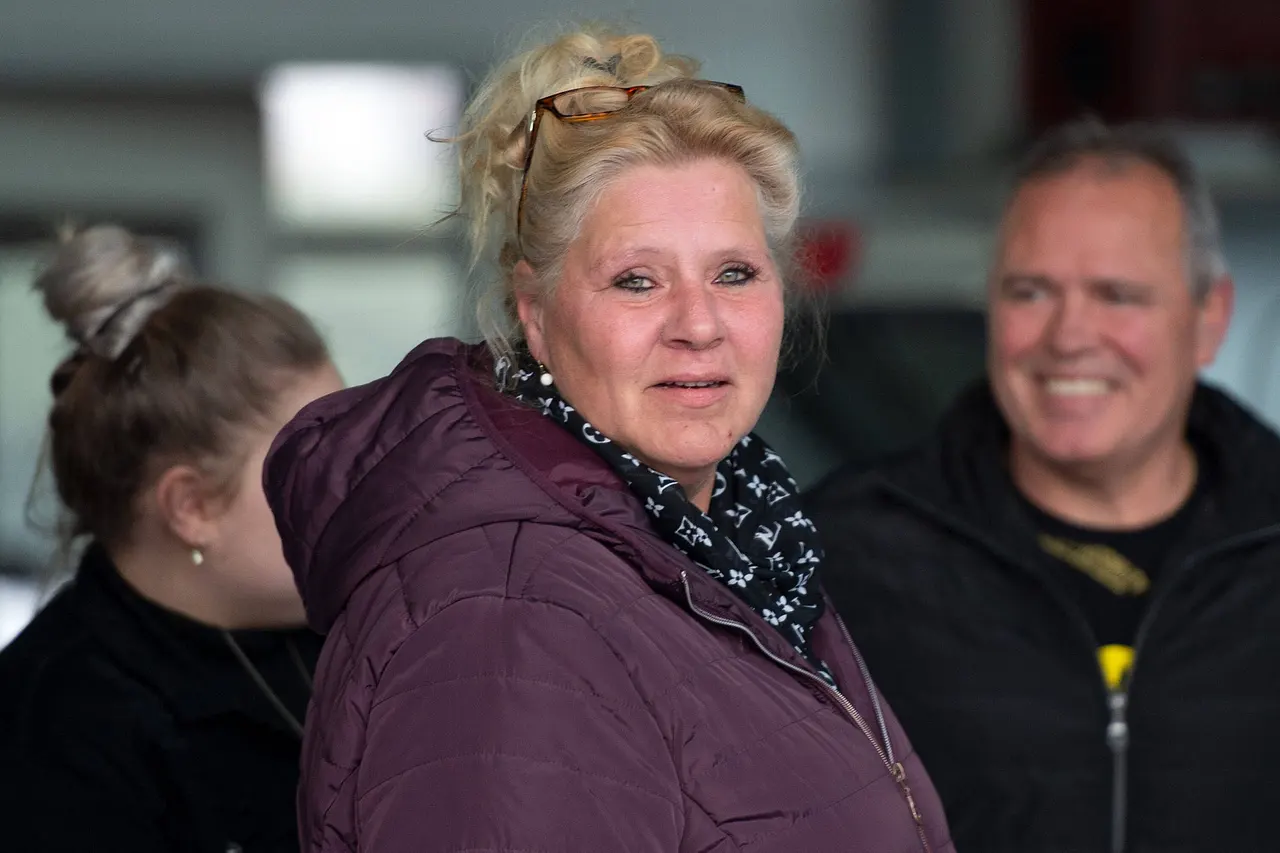 Silvia Wollny steht im Vordergrund und schaut in die Kamera. Sie trägt eine Lila-farbene Winterjacke. Im Hintergrund erkennt man unscharf ihren Lebensgefährten Harald Elsenbast. 