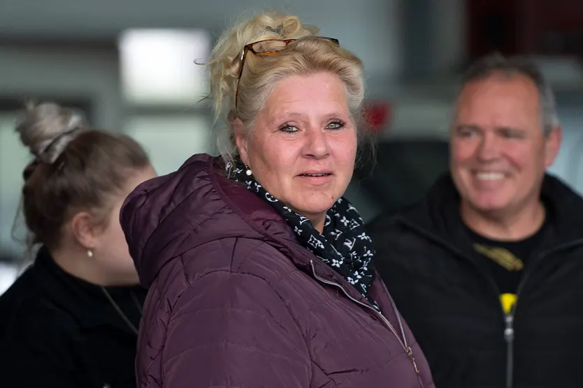 Silvia Wollny steht im Vordergrund und schaut in die Kamera. Sie trägt eine Lila-farbene Winterjacke. Im Hintergrund erkennt man unscharf ihren Lebensgefährten Harald Elsenbast. 