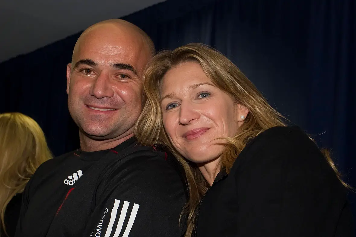 Steffi Graf kuschelt sich lächelnd an Andre Agassi.