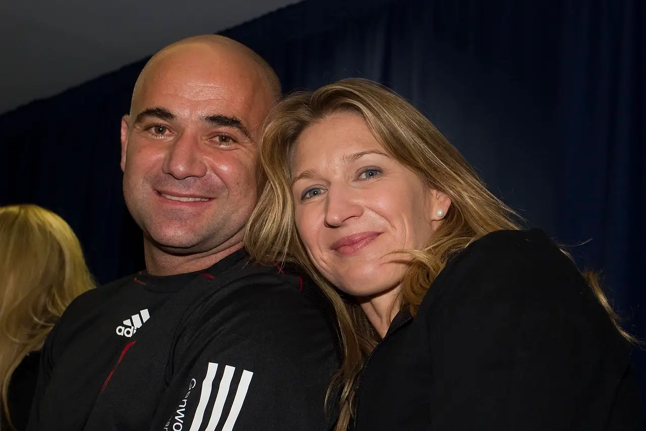 Steffi Graf kuschelt sich lächelnd an Andre Agassi.