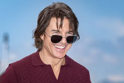 Tom Cruise lächelt breit und zeigt dabei seine Zähne. Er trägt eine Sonnenbrille und die Haare fallen ihm ins Gesicht.