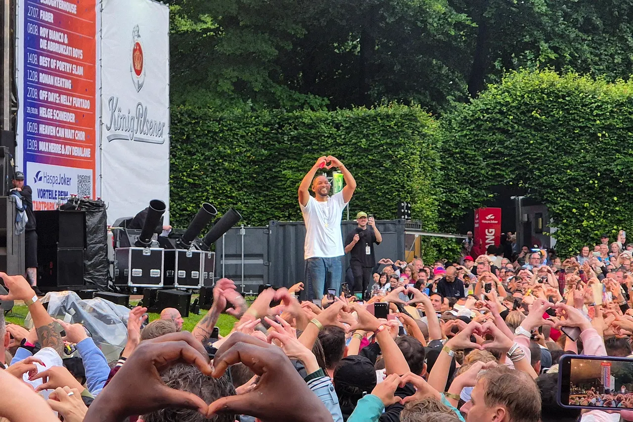 Will Smith steht vor dem Konzertpublikum und formt mit seinen Händen ein Herz.