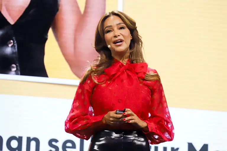 Verona Pooth in einer roten Bluse spricht auf der Bühne.