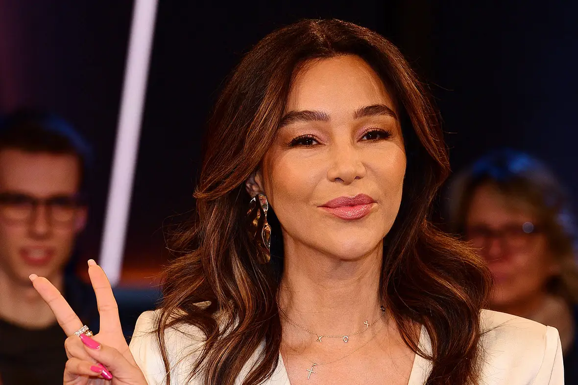 Verona Pooth, hier stark geschminkt und gestylt und ein Peacezeichen machend, ist ausgewandert.