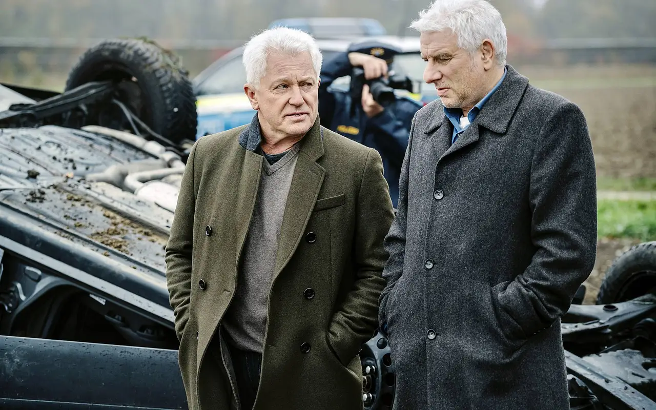 Miroslav Nemec und Udo Wachtveitl stehen vor einem Autowrack. - Foto: ARD