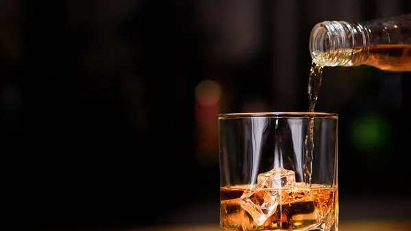Whisky wird in ein Whisky Glas gegossen.